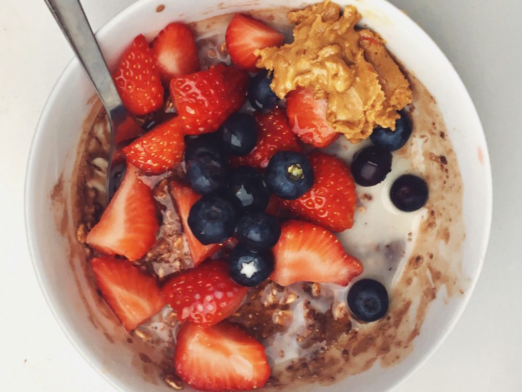 A bowl of overnight oats with strawberries, blueberries and peanut butter