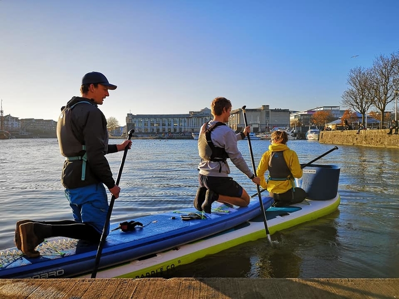 Three people in a boat cleaning Bristol Harbour