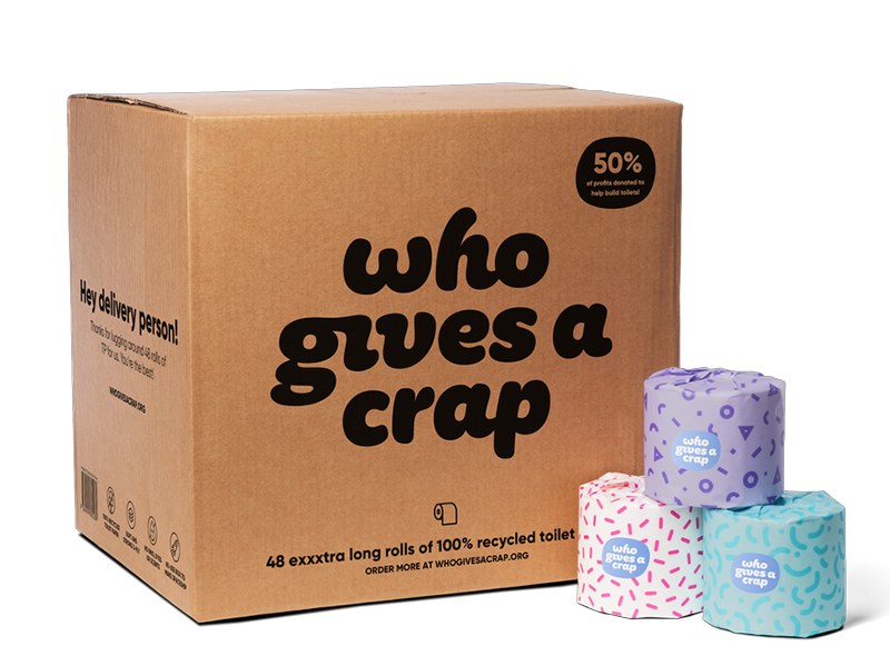 A cardboard box with 'Who Gives A Crap' written on the front. Next to it are three toilet roll packaged in colourful paper.