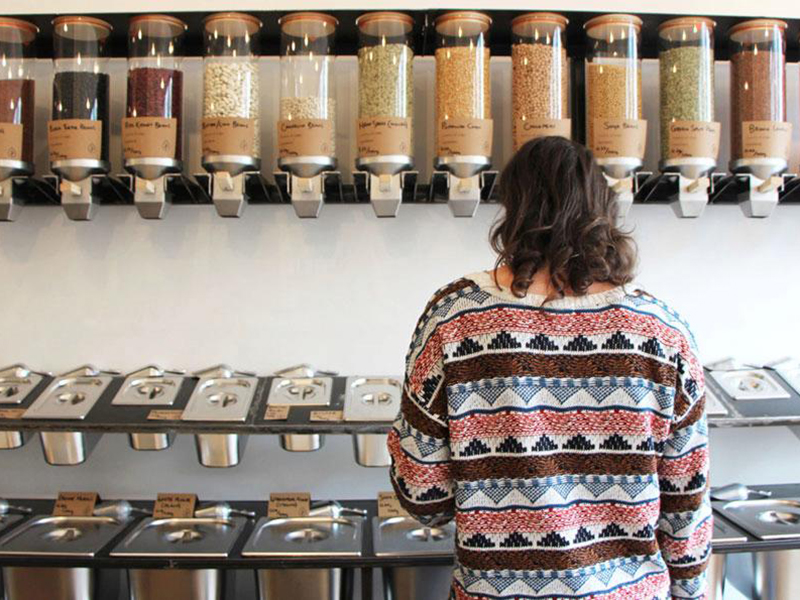 A woman shopping in a plastic-free shop, with several dispensers in front of her