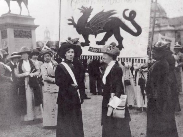 Suffragettes in Cardiff with the Welsh flag in the background