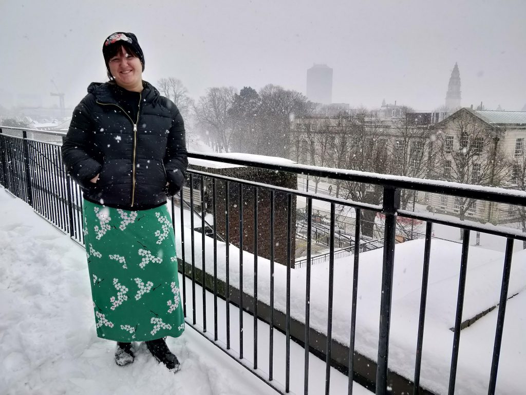 Olivia Williams, 22, poses on a balcony in the snow wearing a bold green skirt.
